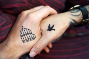 zwei hände mit tattos Käfig und vogel